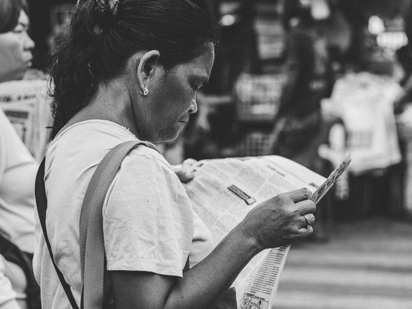 grayscale photo of woman reading newspaper