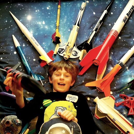 Boy surrounded by model rockets